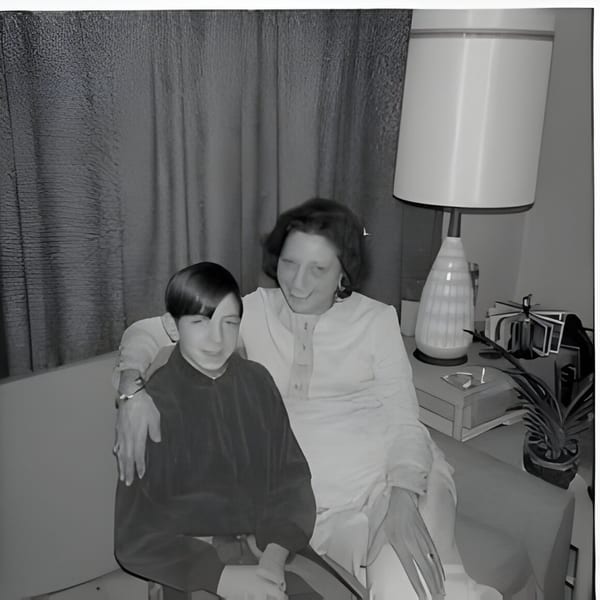Two people, one older and one younger, sitting together on a couch in a black and white photo.