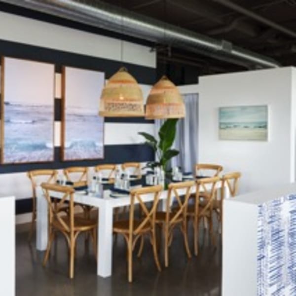 A long dining table with wooden chairs, wicker light fixtures, and ocean-themed artwork at Lena's.