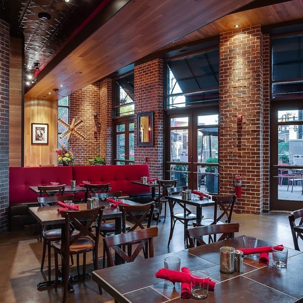 Lena's Wood-Fired Pizza & Tap dining room with red booths, wooden tables, and brick walls.
