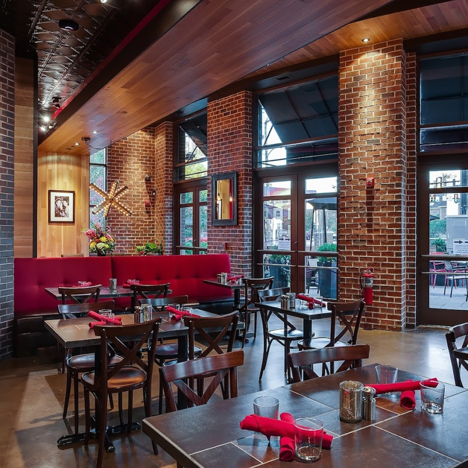 Lena's Wood-Fired Pizza & Tap dining room with red booths, wooden tables, and brick walls.