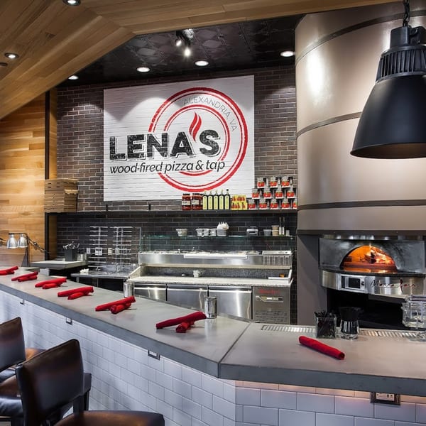 Lena's Wood-Fired Pizza & Tap interior with a large pizza oven and counter seating.