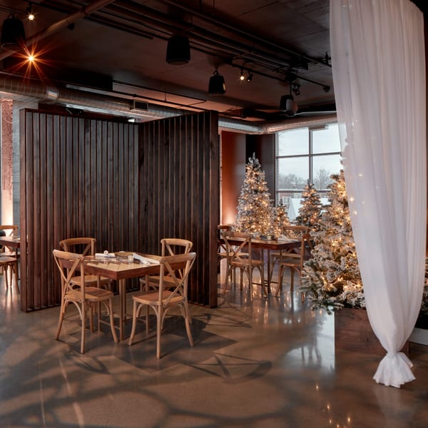Lena's Wood-Fired Pizza & Tap dining area with wooden tables, chairs, and illuminated Christmas trees.