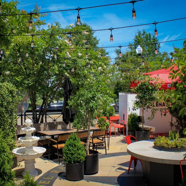 Lena's Wood-Fired Pizza & Tap outdoor patio with string lights, trees, and a fountain.