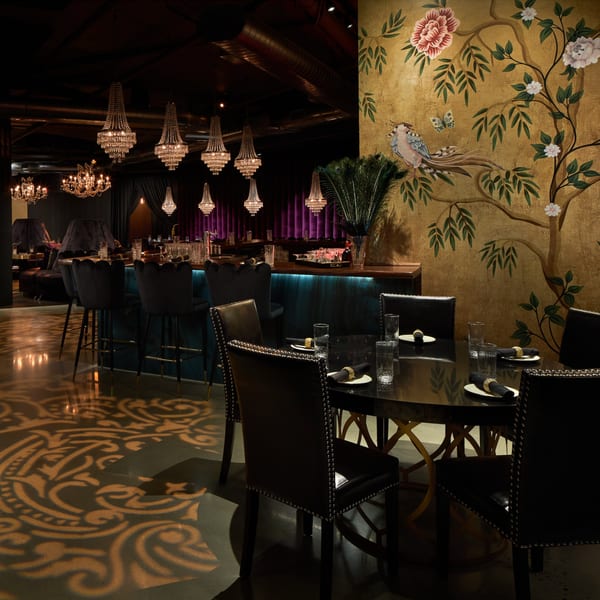 Lena's Wood-Fired Pizza & Tap dining room with chandeliers, bar, and a gold floral mural.