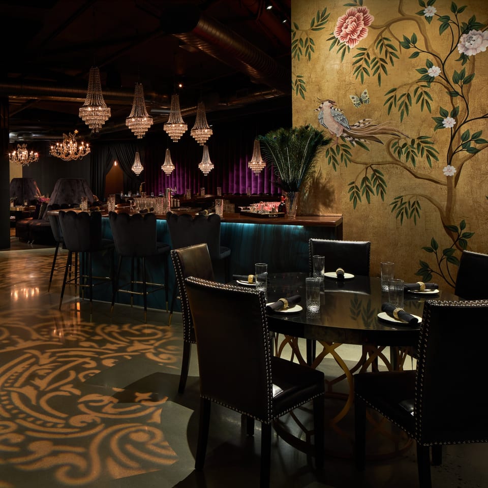 Lena's Wood-Fired Pizza & Tap dining room with chandeliers, bar, and a gold floral mural.