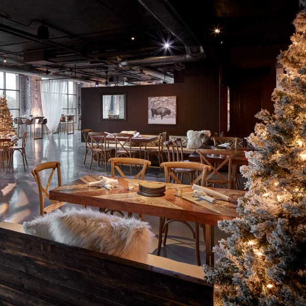 Lena's Wood-Fired Pizza & Tap dining room with wooden tables, chairs, and a frosted Christmas tree.