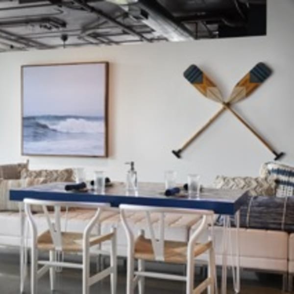 Lena's Wood-Fired Pizza & Tap dining area with a blue table, white chairs, and nautical decor.