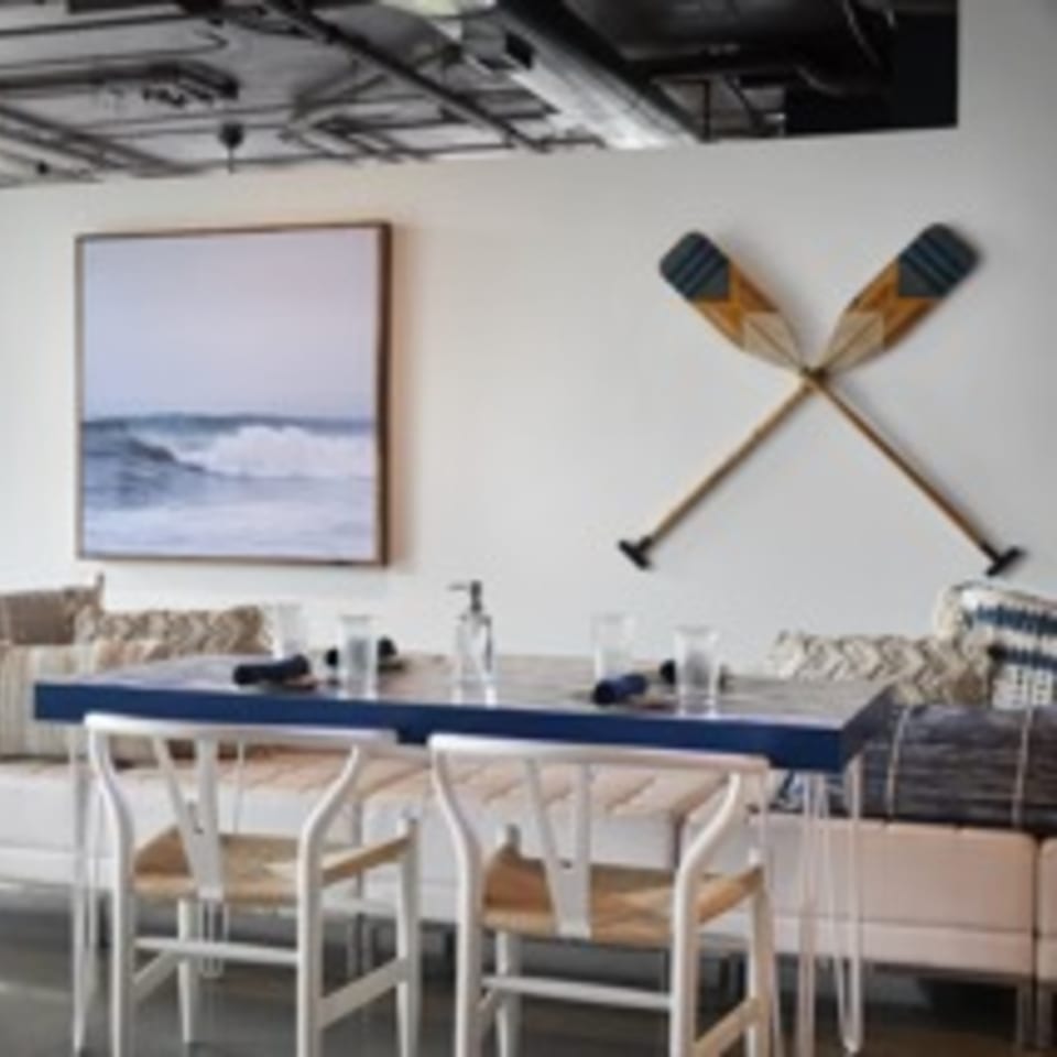 Lena's Wood-Fired Pizza & Tap dining area with a blue table, white chairs, and nautical decor.