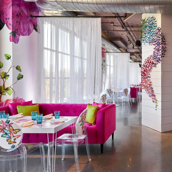 Lena's Wood-Fired Pizza & Tap dining room with bright pink sofas, butterfly decor, and sheer white curtains.