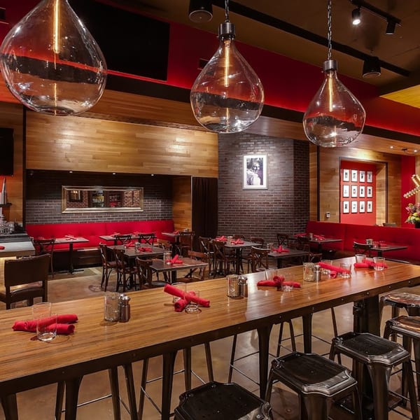 Lena's Wood-Fired Pizza & Tap dining room with long communal table, red booths, and brick walls.