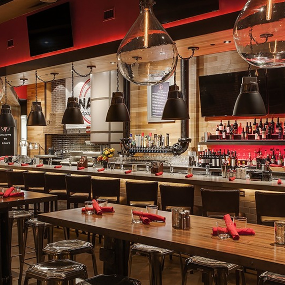 Lena's Wood-Fired Pizza & Tap interior with a long bar, high-top tables, and red accents.