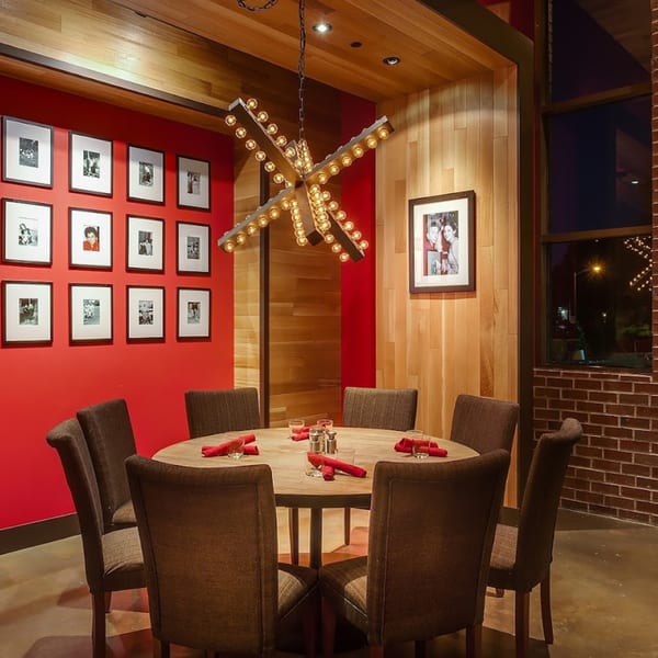 Lena's Wood-Fired Pizza & Tap dining area with a round table, red napkins, and a red accent wall.