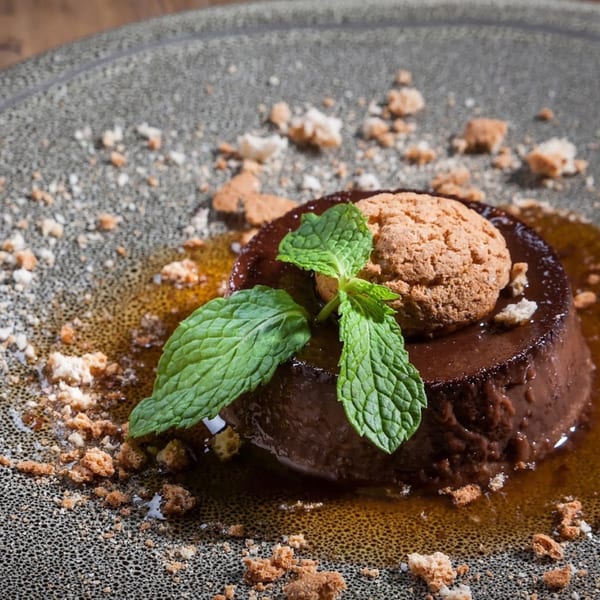 Lena's chocolate dessert with mint, a cookie, and cookie crumbles on a gray plate.