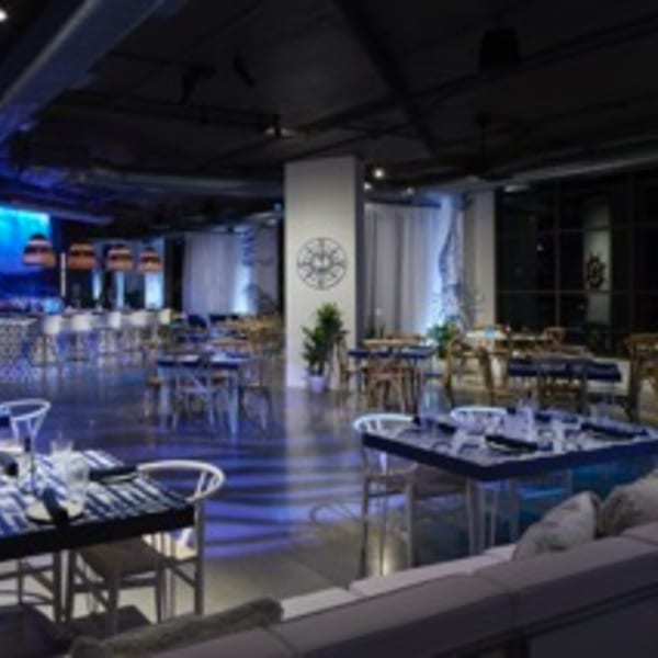 Lena's Wood-Fired Pizza & Tap dining room with blue lighting, set tables, and a bar area.