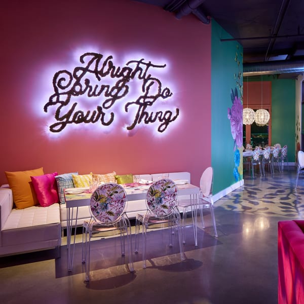 A vibrant dining area at Lena's with a neon sign, colorful walls, and modern seating.