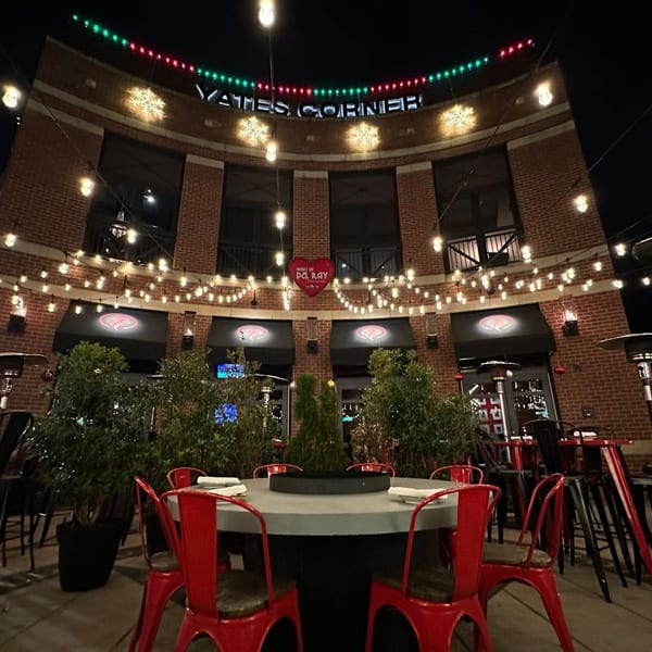 Lena's Wood-Fired Pizza & Tap exterior at night, with string lights, red chairs, and brick.