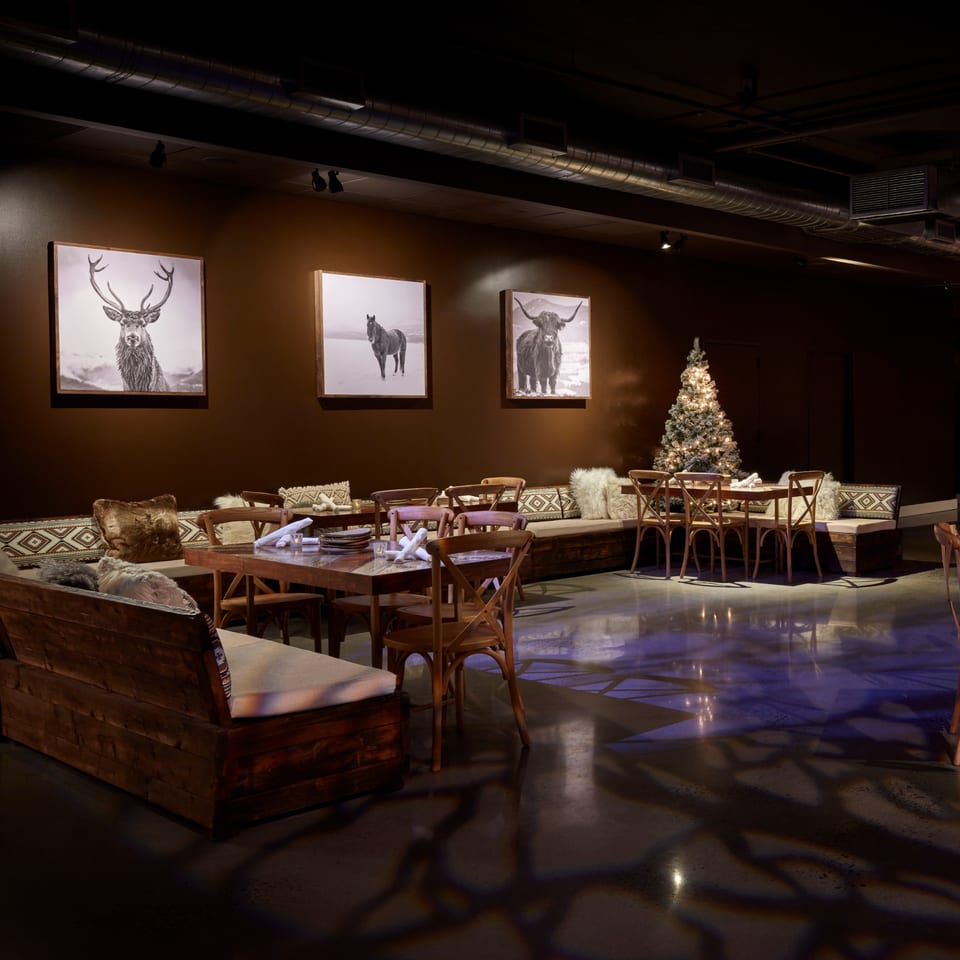 Lena's Wood-Fired Pizza & Tap dining room with dark walls, wooden tables, benches, and a lit Christmas tree.