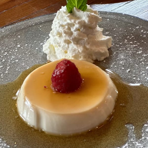 Lena's Panna Cotta, a creamy Italian dessert with raspberry, caramel, whipped cream, and mint.