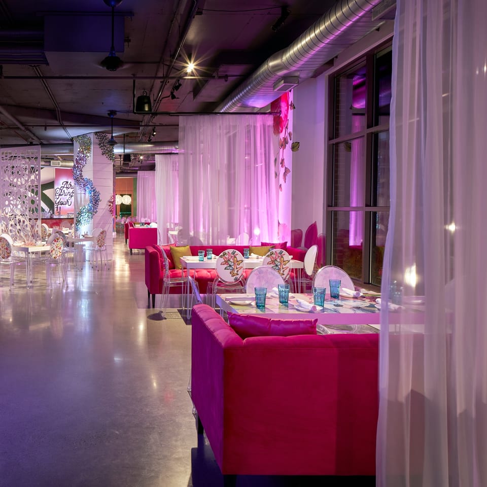 Lena's Wood-Fired Pizza & Tap dining room with hot pink sofas, white tables, and sheer curtains.